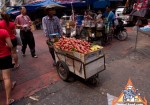 在繁忙的泰国市场推动一辆水果购物车